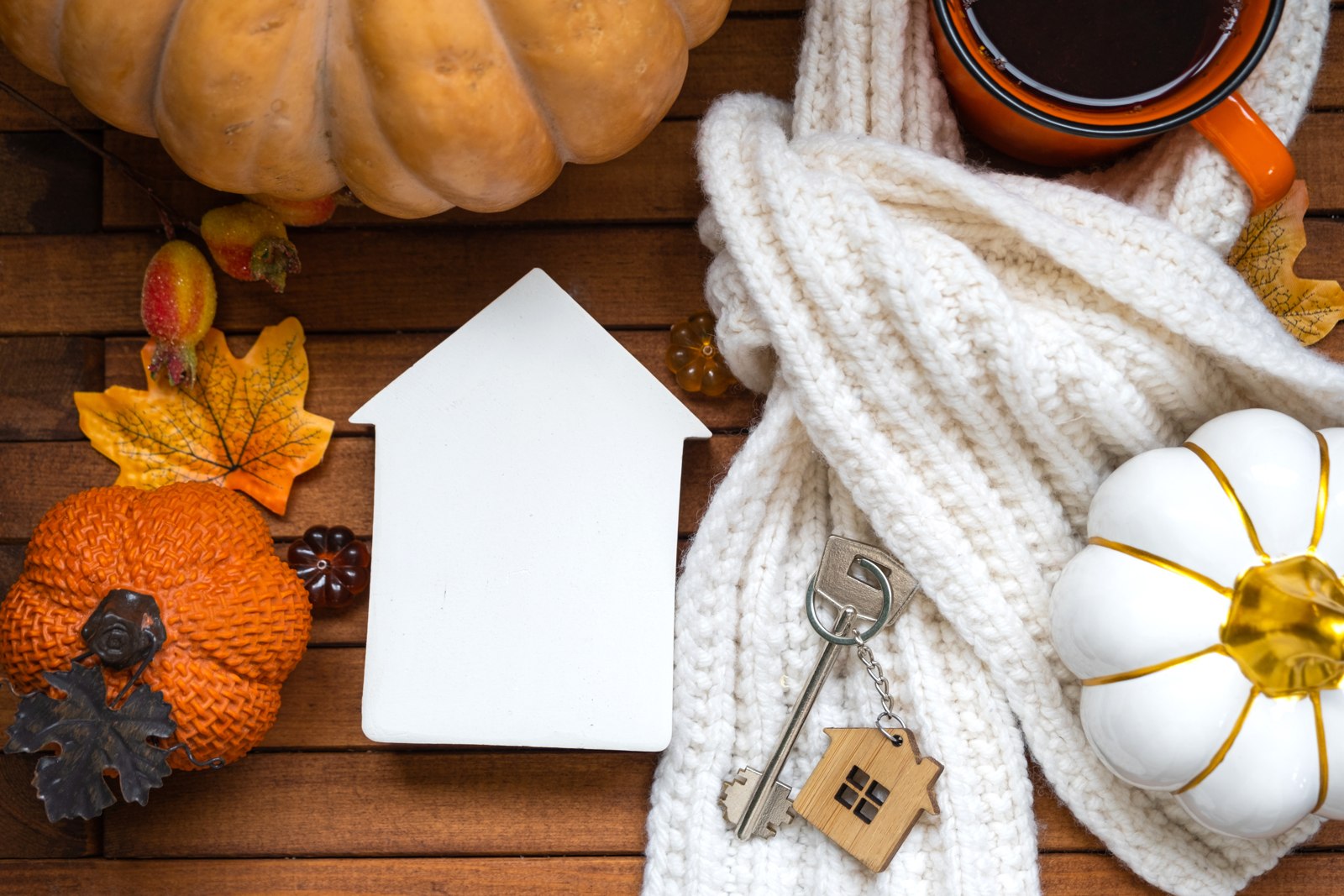 Autumn moving concept with a house, keys, and fall leaves